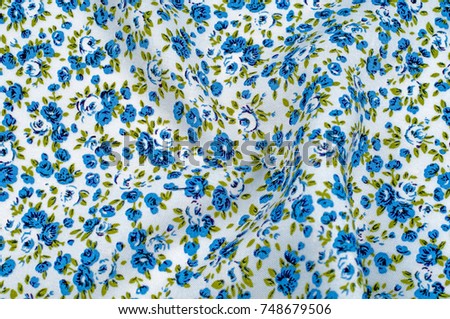 Background texture, pattern. thin cotton fabric with small blue flowers. Fabric has a white background with olive green flower stems and a mixture of tiny blue - aqua flowers. 