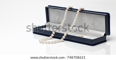 White pearl necklace in a black velvet box on isolated white background. Royalty-Free Stock Photo #748708621