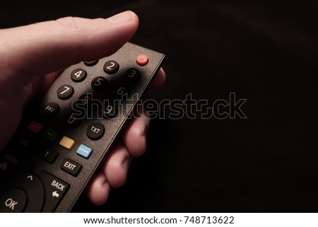 A TV remote control with on off button in focus.
