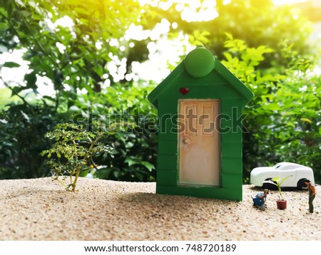 Miniature Greenhouse concept, alone of miniature mini figures with planting tree in front of the green house. protect nature and environment concept