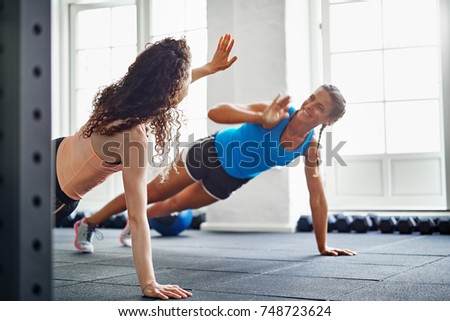 Two smiling young female friends in sportswear doing pushups and high fiving together on the floor of a gym Royalty-Free Stock Photo #748723624