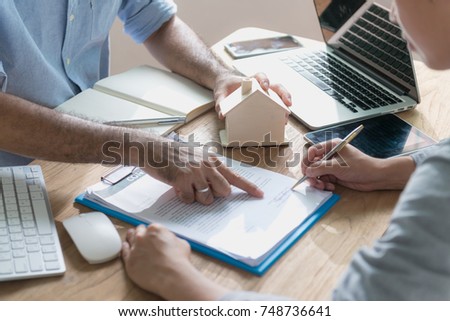 Business concept : Close up view of home rental company staff showing house rental contract agreement document to the customer before sign at the office. Document in picture is fake.