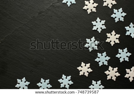 White and blue sugar snowflakes on black background with space for your message