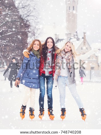 Beautiful skating girls. Open air rink at winter. Falling snow. Christmas concept. 