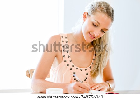 Young woman writing in an agenda at home or office