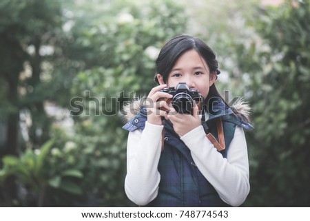 Beautiful Asian girl  in warm clothes with retro  camera shooting a photo in the park