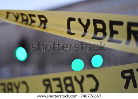 A plastic yellow security tape with the text cyber. Three blurred green lights between a yellow platic tape.