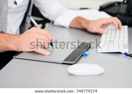 hands detail close-up of male photographer editing photography with a computer and graphic tablet
