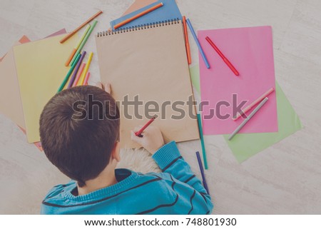 Writing letter to santa. Cute boy makes wish list of presents for christmas. Drawing picture. Prepare for winter holidays, top view of child on floor