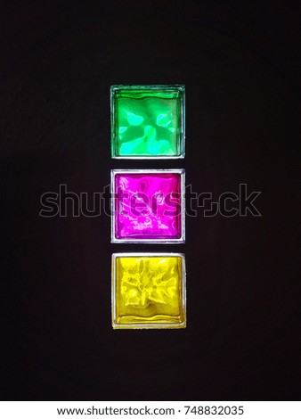 Translucent bricks that let light pass through with pink,  yellow and green colours on a dark background