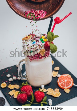 Glass of strawberry milkshake with whipped cream and fresh strawberries