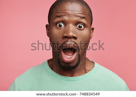 Indoor picture of scared bugged eyed African American male looks with bated breath, horrified to hear shocking news from relatives, finds out about serious disease of his mother. Surprisment concept