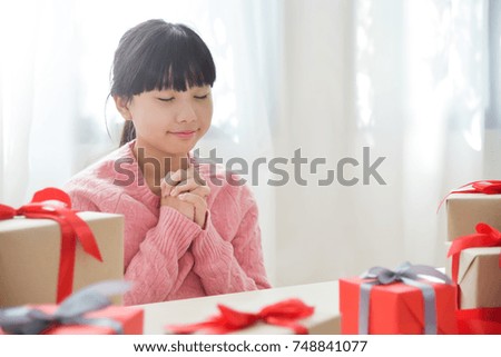 Asian girl making a wish for Birthday, Christmas and New year with gift boxes  in a white room. Copy space.