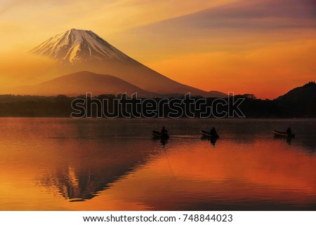 Mt. Fuji or Fujisan with Silhouette three fishing people on boats and mist at Shoji lake with twilight sky at sunrise in Yamanashi, Japan. Landscape with beautiful skyline reflection on the water. Royalty-Free Stock Photo #748844023