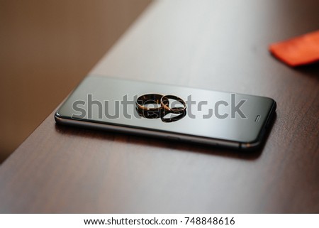 Wedding rings lie on the mobile phone during wedding gatherings.