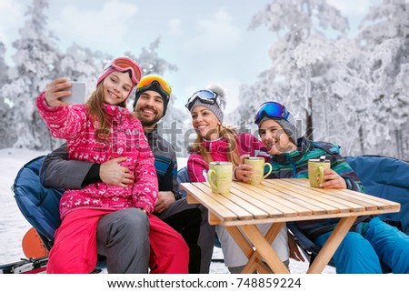 young girl with family laughing and enjoying in winter vacation together on snow and making selfie 