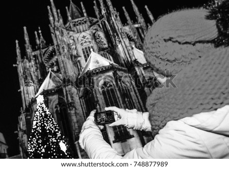 Magic on streets of the old town at Christmas. Seen from behind young tourist woman at Christmas in the front of St. Vitus Cathedral in Prague Czech Republic with digital camera taking photo