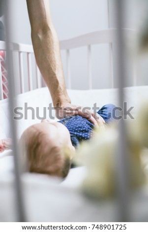 Father holds his hand on tummy little boy lying in bed. Comfort, care, worries, love
