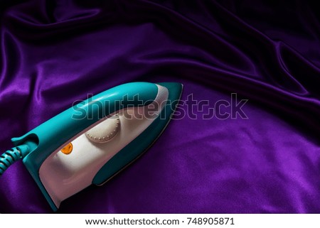 Electric iron on purple fabric ,copy space, house work background