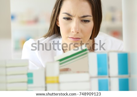 Front view portrait of a doubtful pharmacist checking a medicine in a pharmacy Royalty-Free Stock Photo #748909123