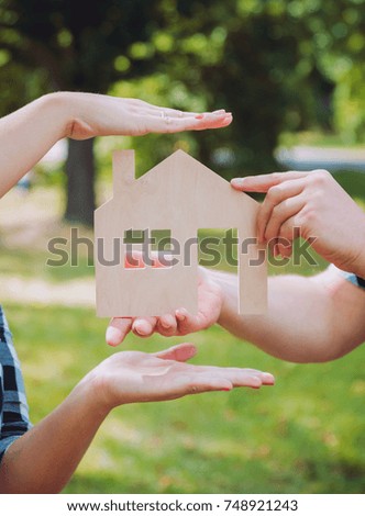 Young woman holding model of house at her hands. Outdoors. Summertime. Real estate and property concept