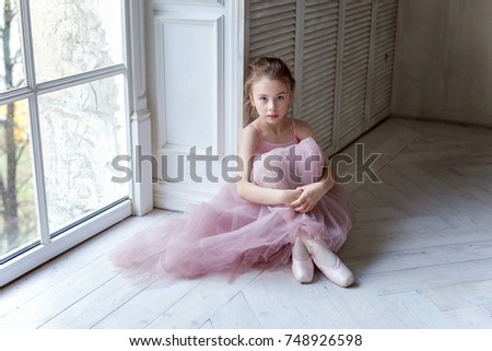 Closeup of young ballerina sit in pointe shoes at white wooden floor background, with copy space. Ballet practice. Beautiful slim graceful ballet dancer