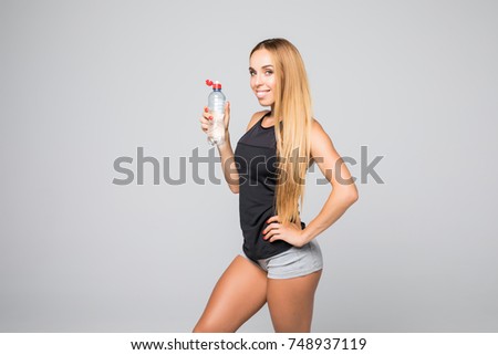 Beautiful woman with water bottle in sport wear over gray