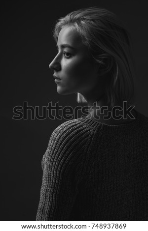 A young blond woman near black background. black and white