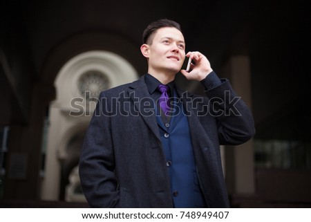 Modern businessman talking on a smartphone on a dark background of the city.