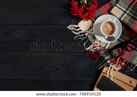 Above view of Smart phone with notebook and cup of latte coffee on black wooden background.