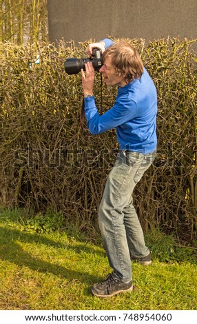 A photographer getting into position to take a photograph by crouching slightly from a standing position