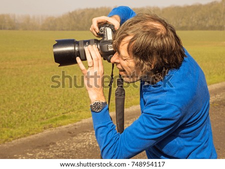 A photographer getting into a standing position to take a photograph