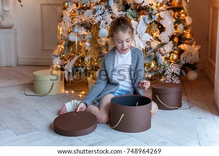 Young girl opens a gift under a Christmas tree