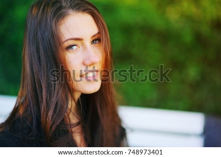 Closeup portrait of happy smiling beautiful young woman in black shirt on the background of blurred green trees. Positive human emotions, cute face, selective focus.