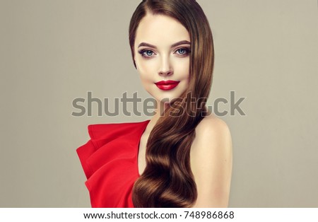 Beautiful  brunette model  girl  with long curly  hair . Hairstyle wavy curls . Red  lips  and dress.  Fashion , beauty and make up portrait Royalty-Free Stock Photo #748986868