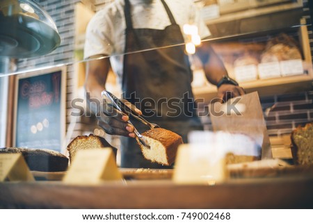 Black man works in pastry shop. Royalty-Free Stock Photo #749002468