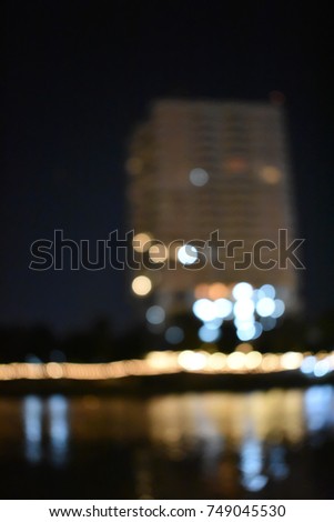 Blurry picture of lighting of building at side of river in the night time. 