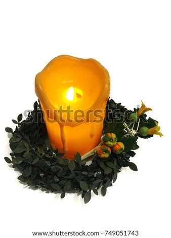 A green wreath, a pumpkin flower model and a candle on white background are decoration items for Thanksgiving Day and also Christmas.