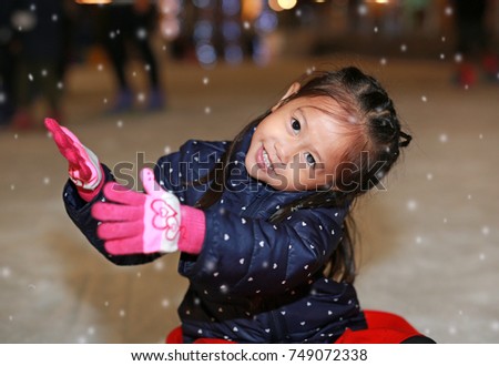 Smiling little girl wearing jacket has a fun in snow.