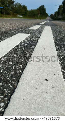 White line sign on black asphalt road, close up background
