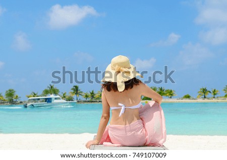 Beautiful asian young woman in sunhat sitting relaxed on sand, tropical beach in Maldives
