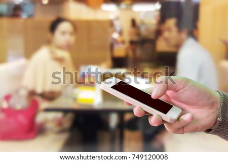 Man use mobile phone, blur image of Lovers have diner in the restaurant.