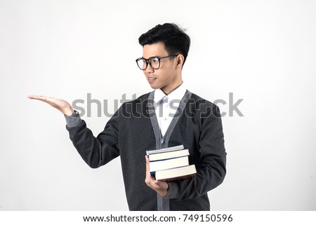 Young nerdy student is standing with books in glasses hand present something - copyspace