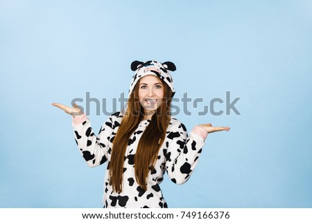 Happy teenage girl in funny nightclothes, pajamas cartoon style presenting something, holding open empty hands with positive face expression, studio shot on blue. Advertisement concept.