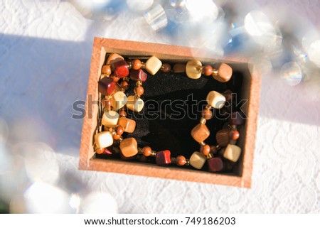 Wooden box with wooden jewelery necklace on it. Carved necklace and earrings from light wood. Bokeh on picture sides