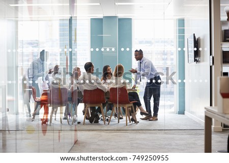 Young male boss stands leaning on table at business meeting Royalty-Free Stock Photo #749250955