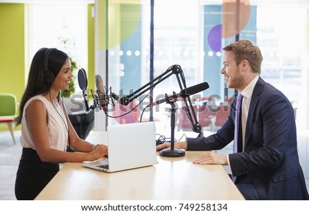 Young woman interviewing a guest in a studio for a podcast