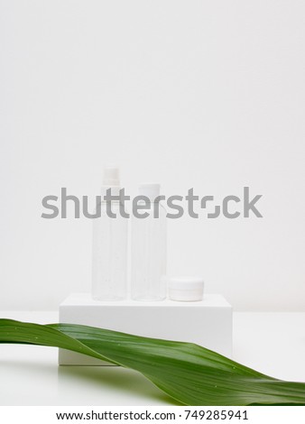 Minimal style. Minimalist beauty and fashion photography. Cosmetic body cream near the flower arrangement. Trendy minimal style with colorful paper backdrop