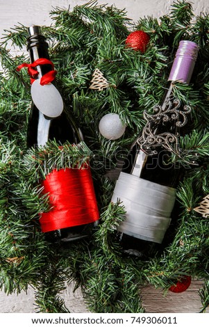 Photo of two Christmas bottles with clean greeting card on spruce branches