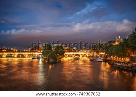 Nighttime view of la Cite in Paris, France, with Pont Neuf and Seine river. Spectacular travel background.